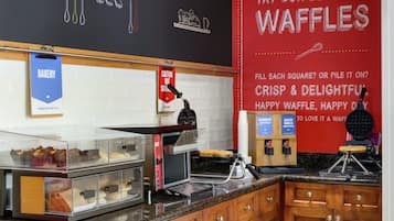 A bakery section with waffle makers and a sign advertising delicious waffles.