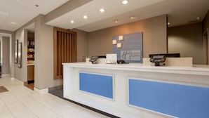 A hotel reception desk with a modern design, a counter, and a sign that reads "Holiday Inn Express". - Holiday Inn Express & Suites Lenoir Cty by IHG (Lenoir City)