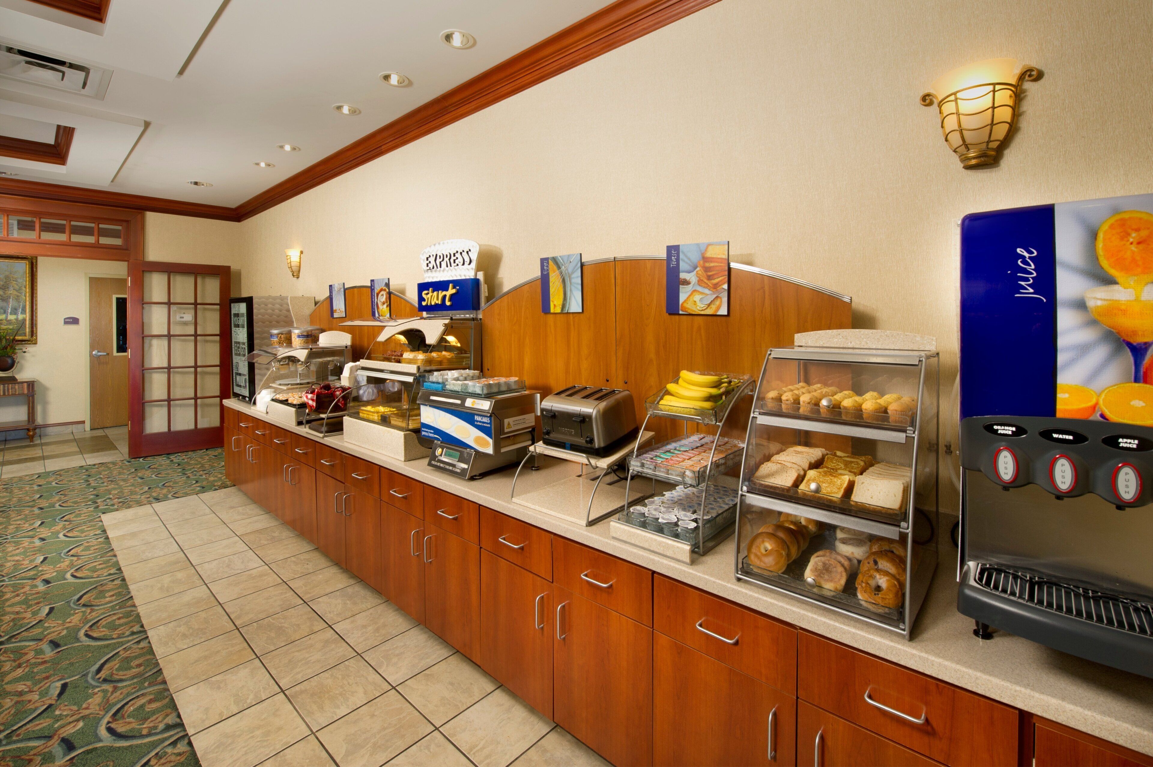 A buffet counter with various food items, a juice dispenser, and a sign indicating the start of the buffet.