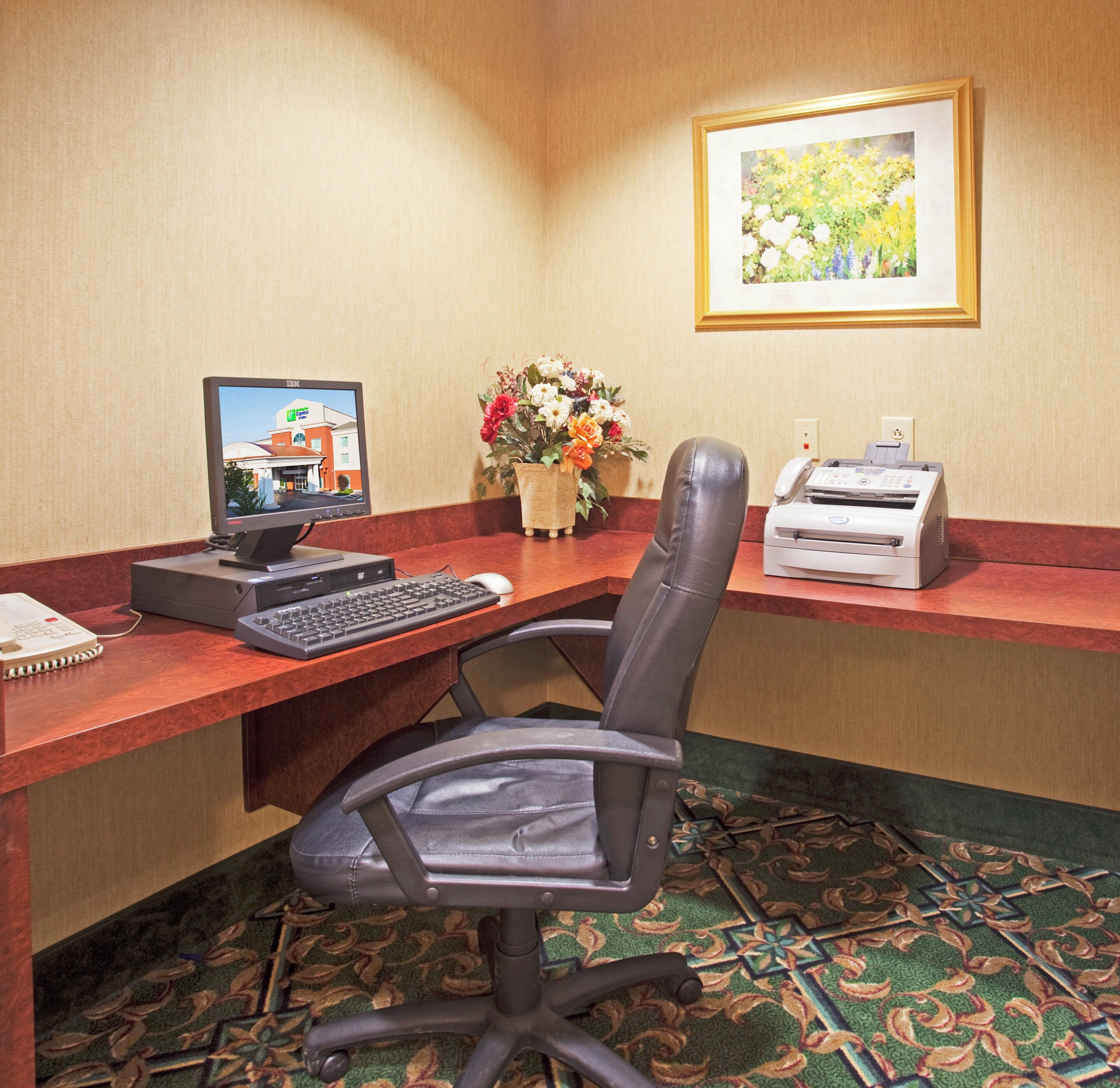 Une chambre d’hôtel équipée d’un bureau, d’un ordinateur, d’une imprimante, d’une chaise et d’un tableau encadré au mur.
