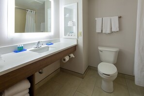 A bathroom with a white sink, mirror, and toilet. There are towels hanging on the wall and a shower curtain. - Holiday Inn Express & Suites Lenoir Cty by IHG (Lenoir City)