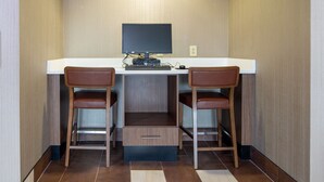 A small, modern room with a desk and two chairs, a flat-screen TV, and a built-in shelf. - Holiday Inn Express & Suites Lenoir Cty by IHG (Lenoir City)