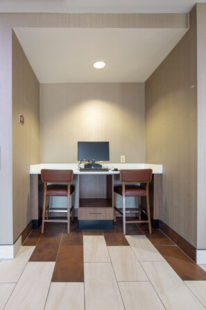 A small, modern room with a desk and two chairs, a flat-screen TV, and a built-in shelf. - Holiday Inn Express & Suites Lenoir Cty by IHG (Lenoir City)