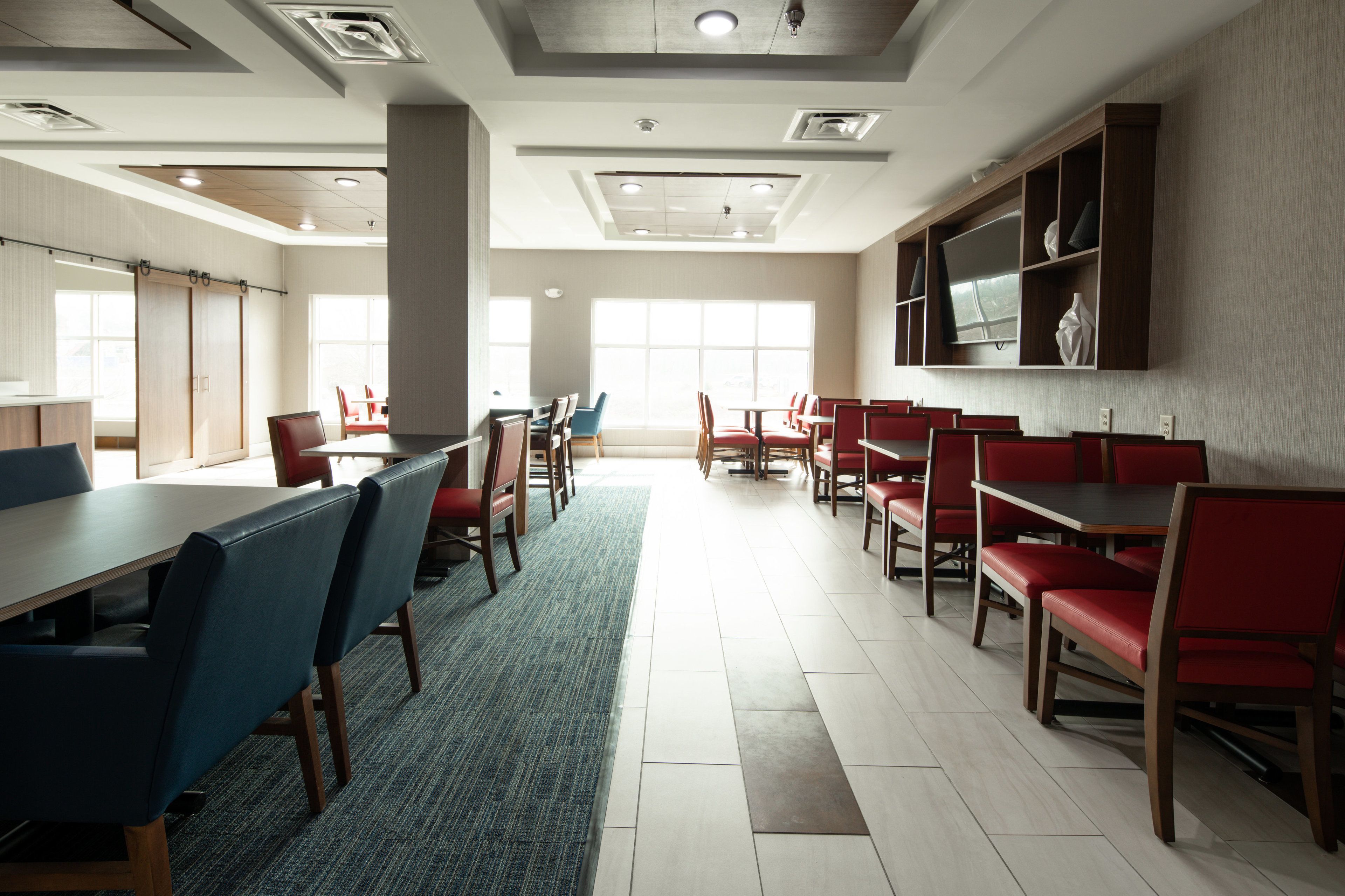 A spacious dining area with high ceilings, large windows, and modern furniture.