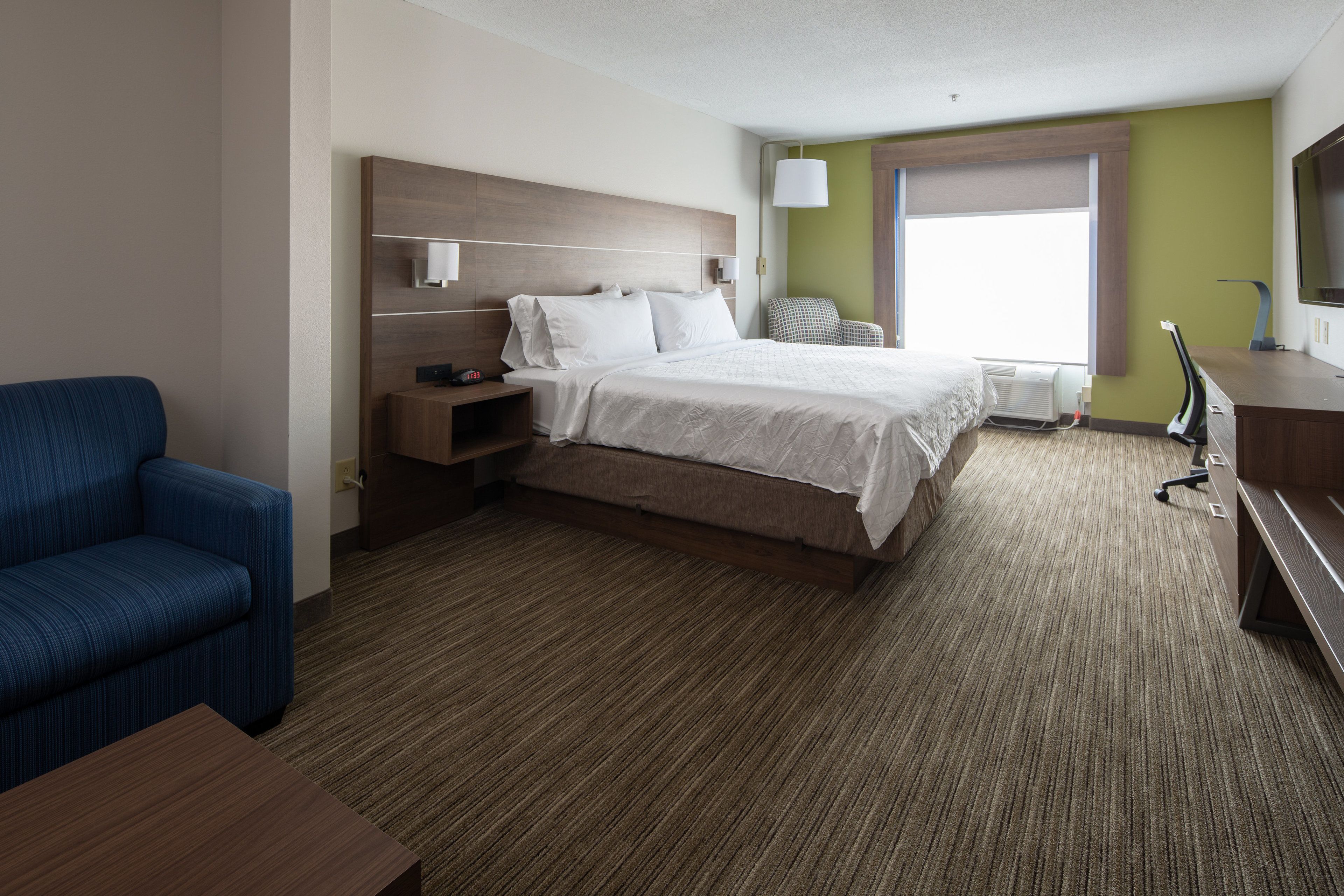 Une chambre d’hôtel avec un grand lit, un bureau, une chaise et un téléviseur.
