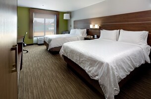 Habitación de hotel con dos camas, un escritorio y una ventana con vistas.