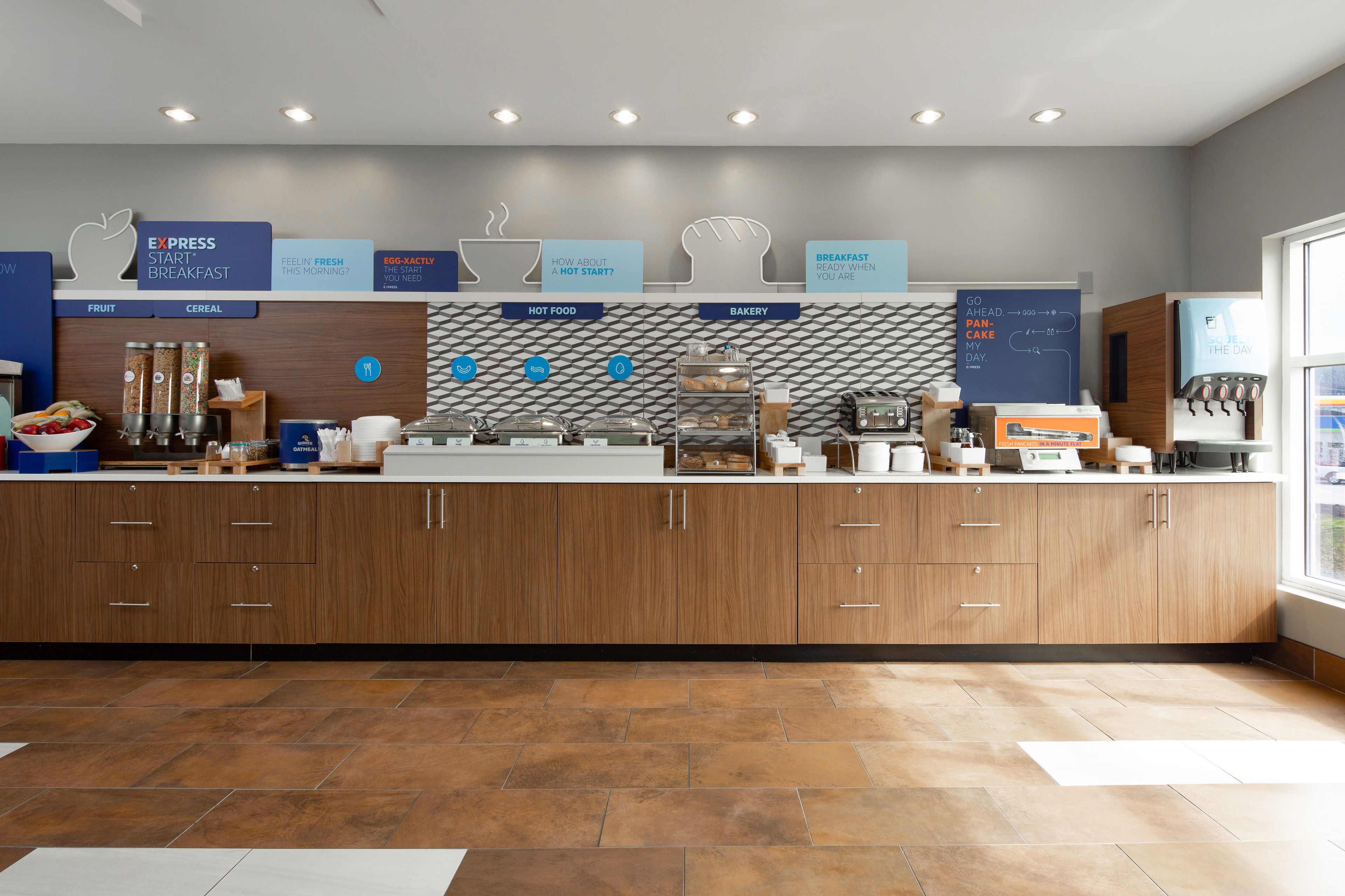 Un buffet moderne pour le petit-déjeuner, avec des présentoirs étiquetés pour les fruits, les céréales, les plats chauds et les produits de boulangerie.