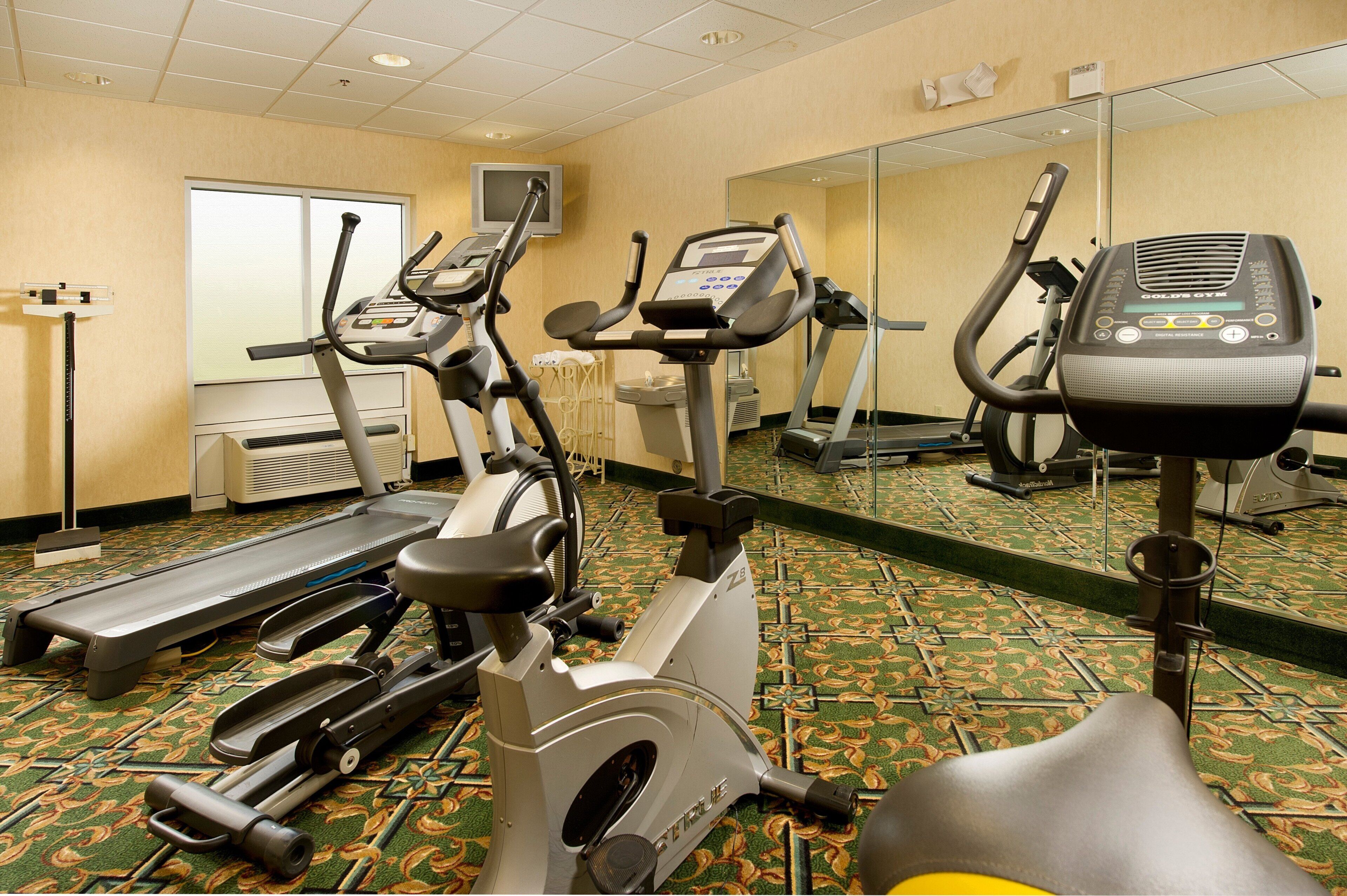 Ginásio de hotel com esteiras, elípticos e bicicleta ergométrica.