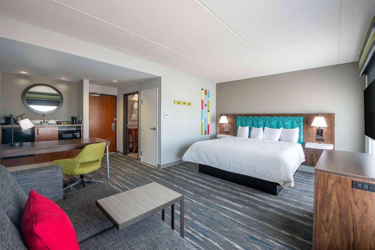Une chambre d’hôtel avec un lit, un bureau et une chaise, une télévision et une petite table.