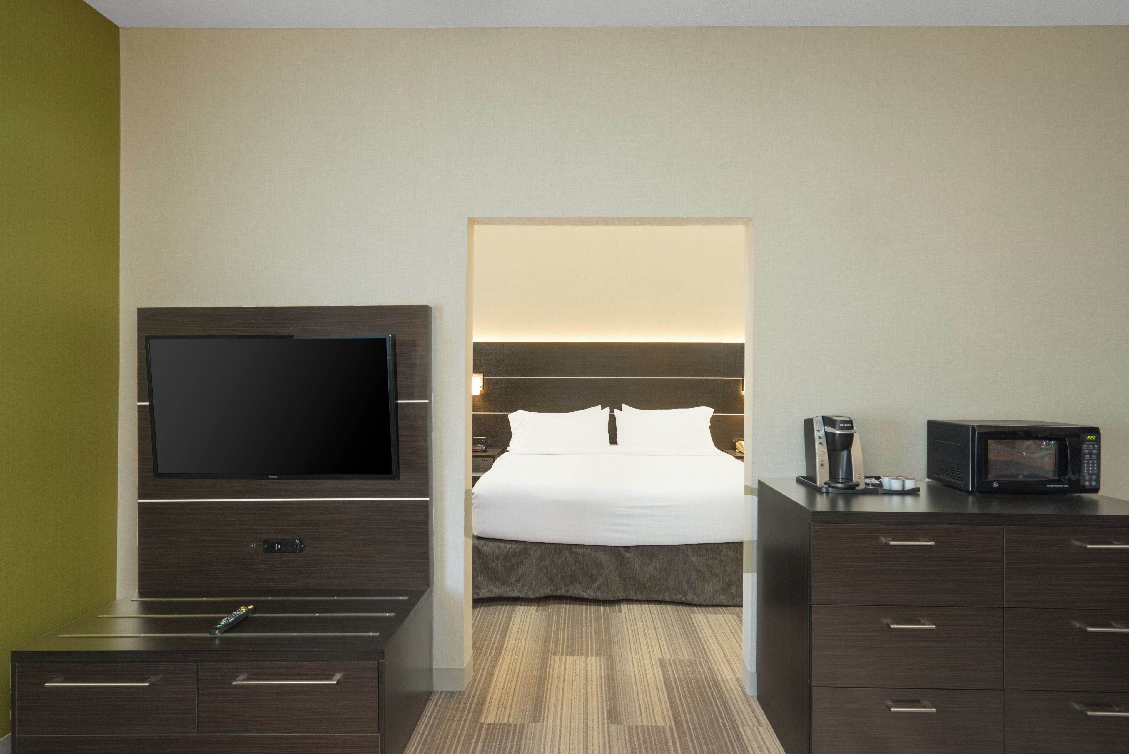 A hotel room with a bed, a television, a coffee maker, and a microwave.