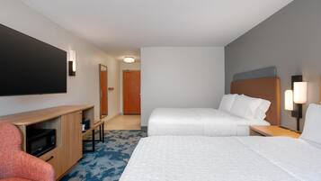 Habitación de hotel con cama, escritorio, silla, televisión de pantalla plana y puerta.