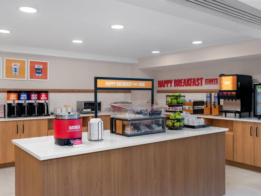 A breakfast station with coffee machines, an oatmeal dispenser, and a juice cooler.
