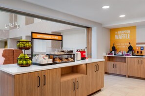 A breakfast station with a sign that reads 'HAPPY BREAKFAST STARTS HERE' and a waffle station with a sign that says 'THE HAMPTON WAFFLE'. - Hampton Inn & Suites Rockland (Thomaston)