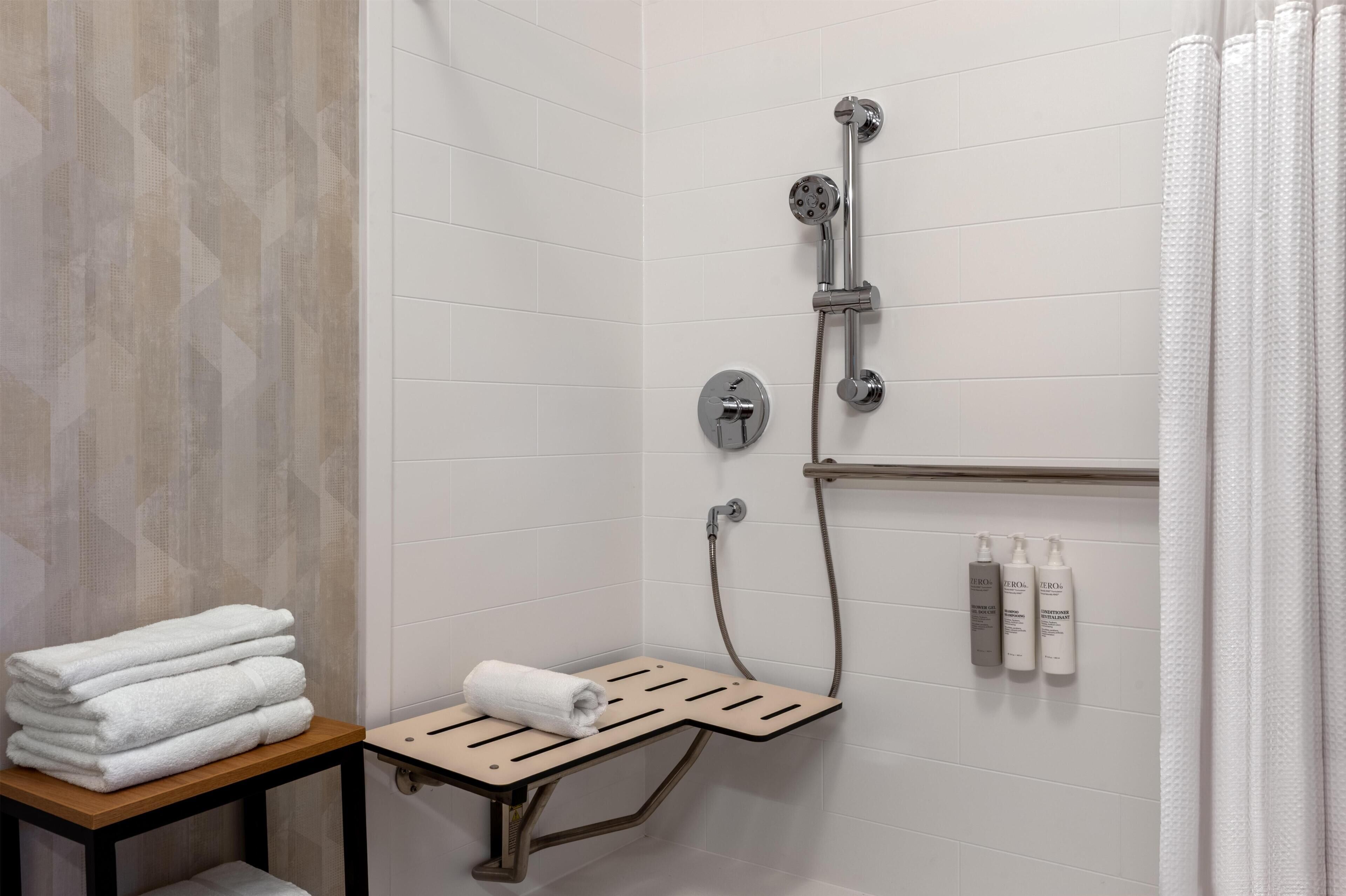 Un espace douche équipé d’un porte-serviettes, d’un pommeau de douche et d’une étagère pour les articles de toilette.