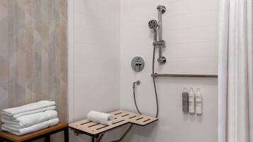 Un espace douche équipé d’un porte-serviettes, d’un pommeau de douche et d’une étagère pour les articles de toilette.