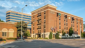 Un hotel con fachada de ladrillo, un letrero de 'Bank of America' y la intersección de dos calles.