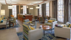 Un vestíbulo de hotel con un bar, zona de estar y comedor.