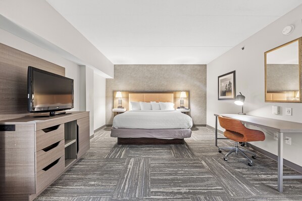 A hotel room with a bed, a desk, a television, and a mirror.