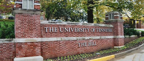 A brick wall with the text "The University of Tennessee The Hill" and a small window above it.