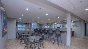 A modern hotel lobby with a reception desk, seating area with round tables and chairs, and a visible exit door. - Microtel Inn & Suites by Wyndham Albertville (Albertville)