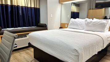 Een moderne hotelkamer met een groot bed, een zithoek met uitzicht en een flatscreen televisie.