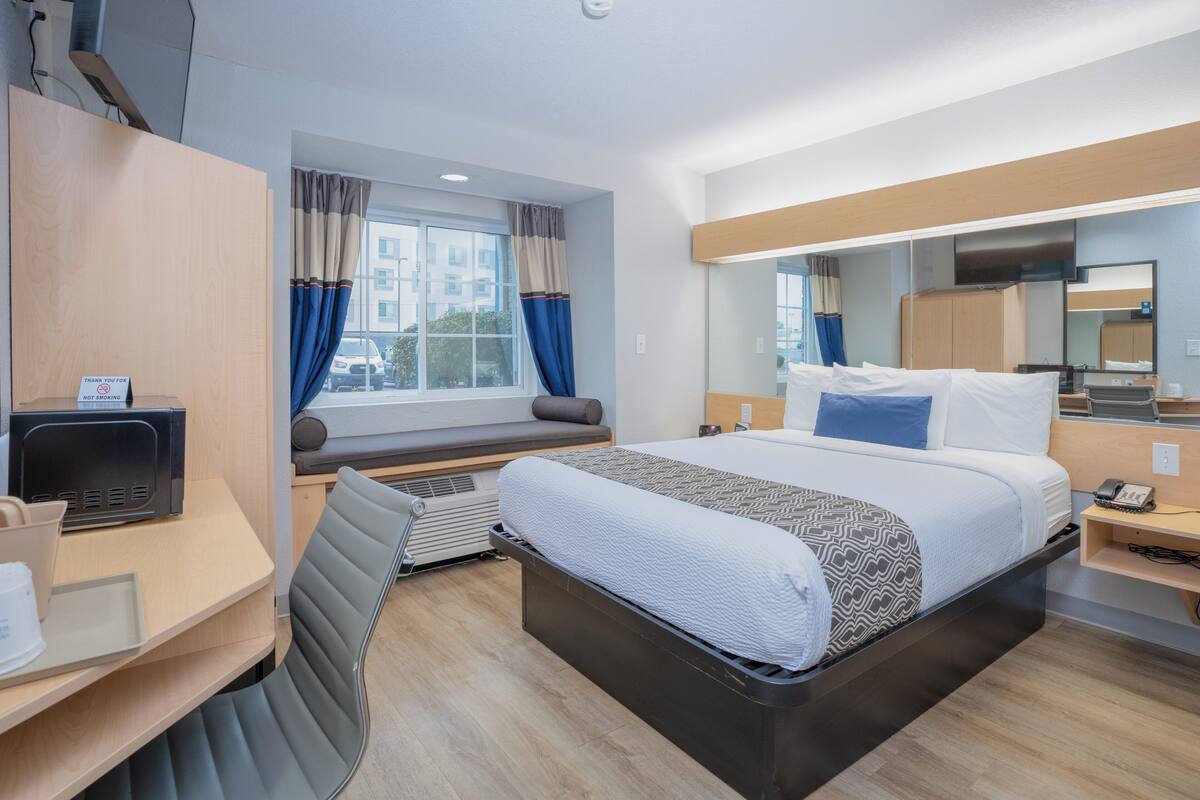 A modern hotel room with a bed, desk, and chair.