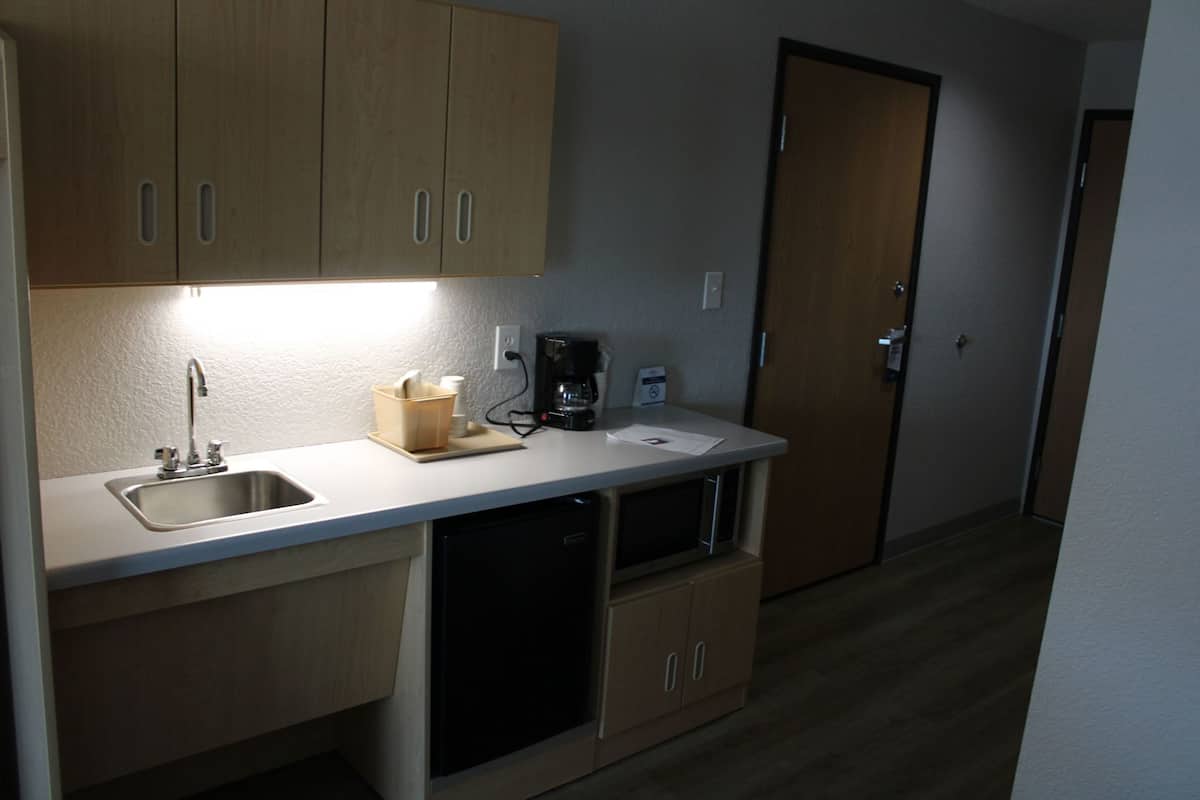 A compact kitchenette with a sink, a coffee maker, and a cabinet.