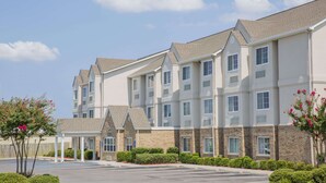 A multi-story hotel with a covered entrance, parking lot, and well-maintained landscaping. - Microtel Inn & Suites by Wyndham Albertville (Albertville)