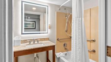 A bathroom with a sink, mirror, shower, and toilet.