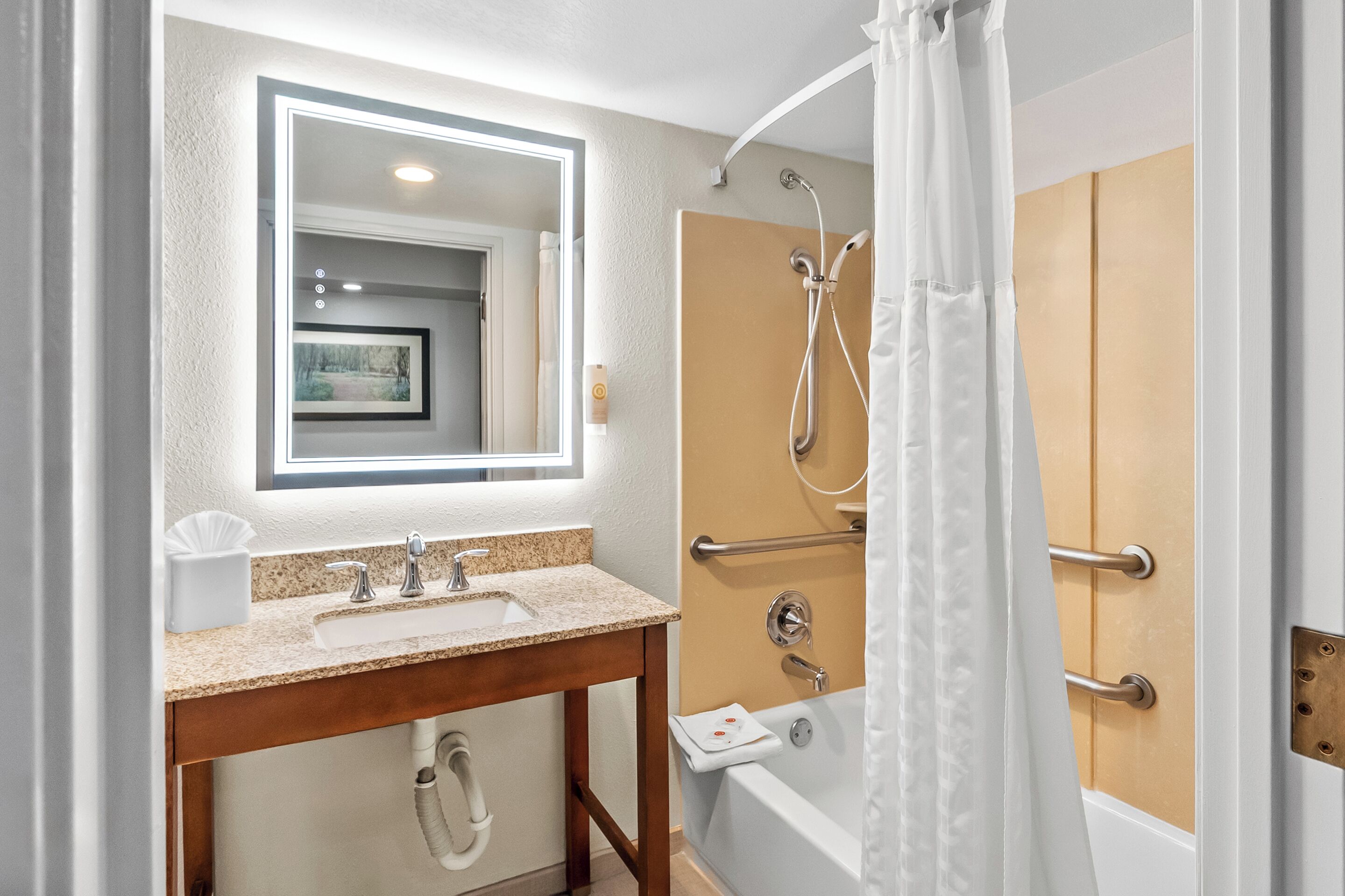 A bathroom with a sink, mirror, shower, and toilet.