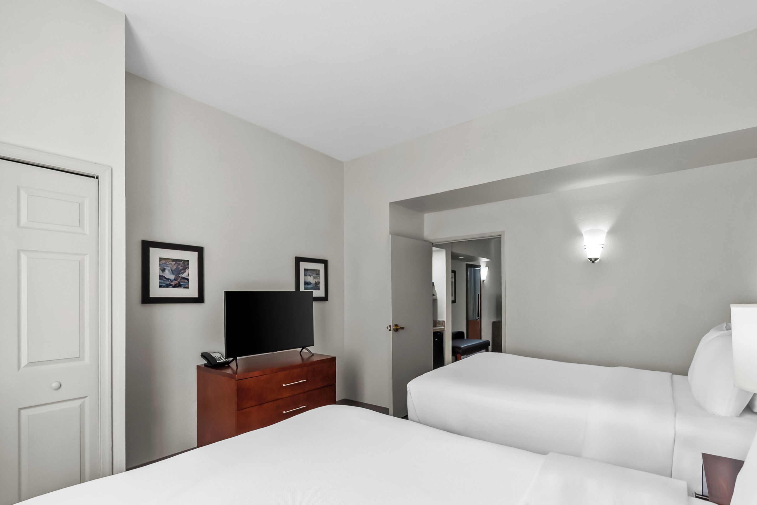 Quarto de hotel com cama, penteadeira, televisão e espelho.