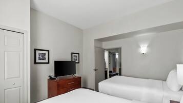 Quarto de hotel com cama, penteadeira, televisão e espelho.