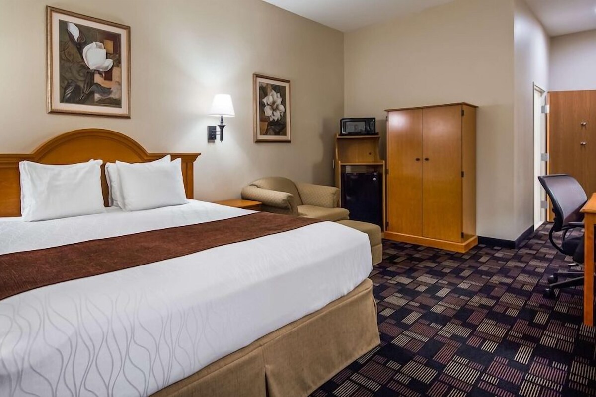 A hotel room with a large bed, a desk, a chair, a wardrobe, and two wall-mounted lamps.
