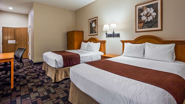 A hotel room with two beds, a desk, a chair, a wardrobe, and two wall-mounted lamps.