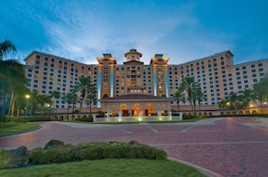 A large hotel with multiple floors, a central courtyard, and palm trees.