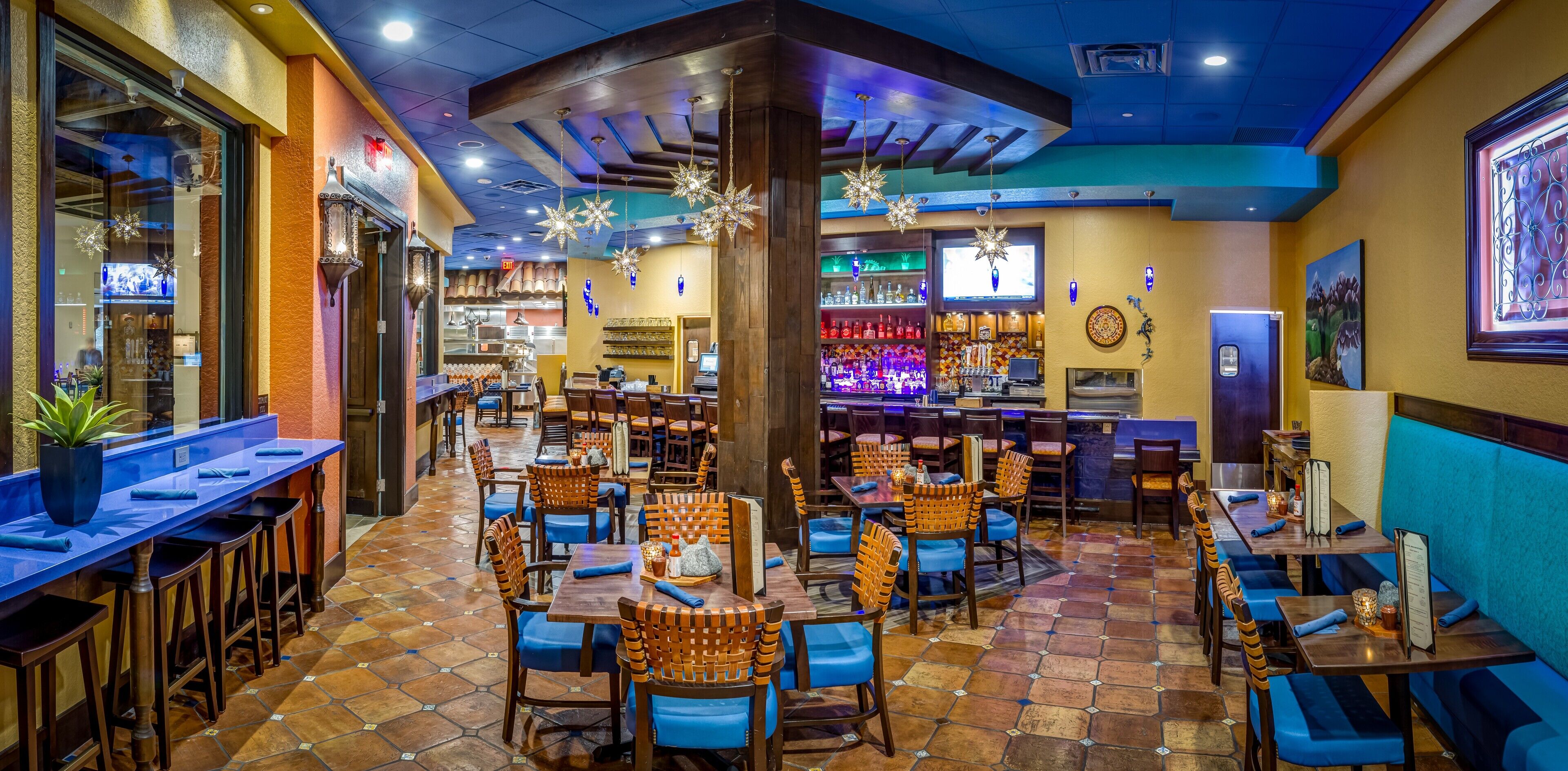 A restaurant with multiple tables and chairs, a bar area, and a counter.