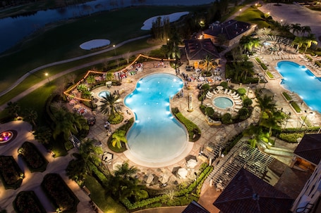 An aerial view of a resort with multiple swimming pools, landscaped gardens, and outdoor seating areas.