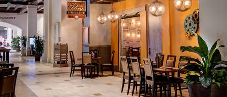 A restaurant with a brick wall, hanging lights, and a sign for 'Taco's Burgers & Brews'.