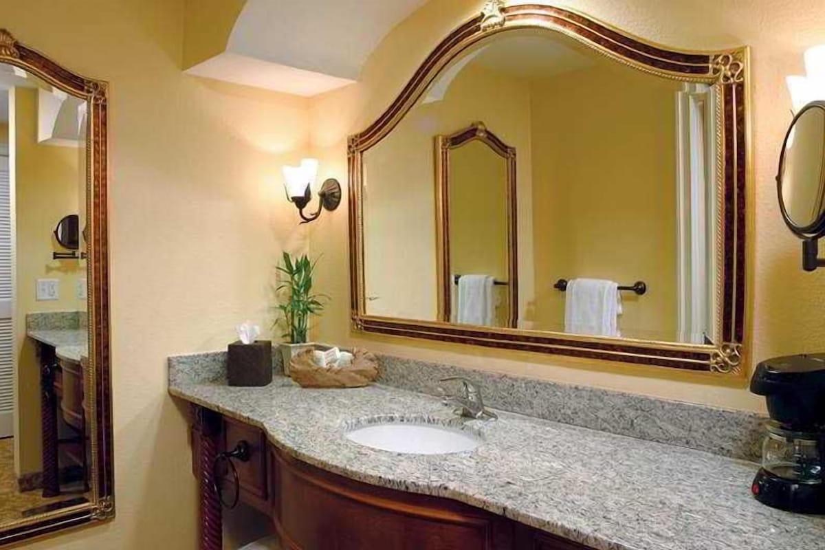 A bathroom with a granite countertop, a sink, a mirror, and a towel rack.