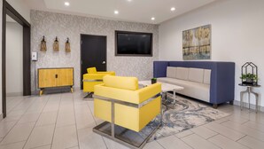A modern living room with a sofa, yellow armchairs, a TV, and a painting on the wall. - Best Western NSU Inn (Tahlequah)