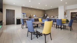 A modern dining area with a central table, blue and yellow chairs, a coffee machine, and a refrigerator. - Best Western NSU Inn (Tahlequah)