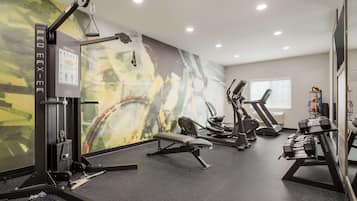 Een sportschool met diverse fitnessapparaten, zoals een bankdrukapparaat, gewichten en cardio toestellen.