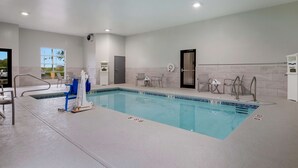 A clean indoor swimming pool with clear lane markings, a changing room, and a door leading to a locker area.
