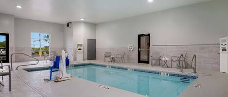 A clean indoor swimming pool with clear lane markings, a changing room, and a door leading to a locker area.