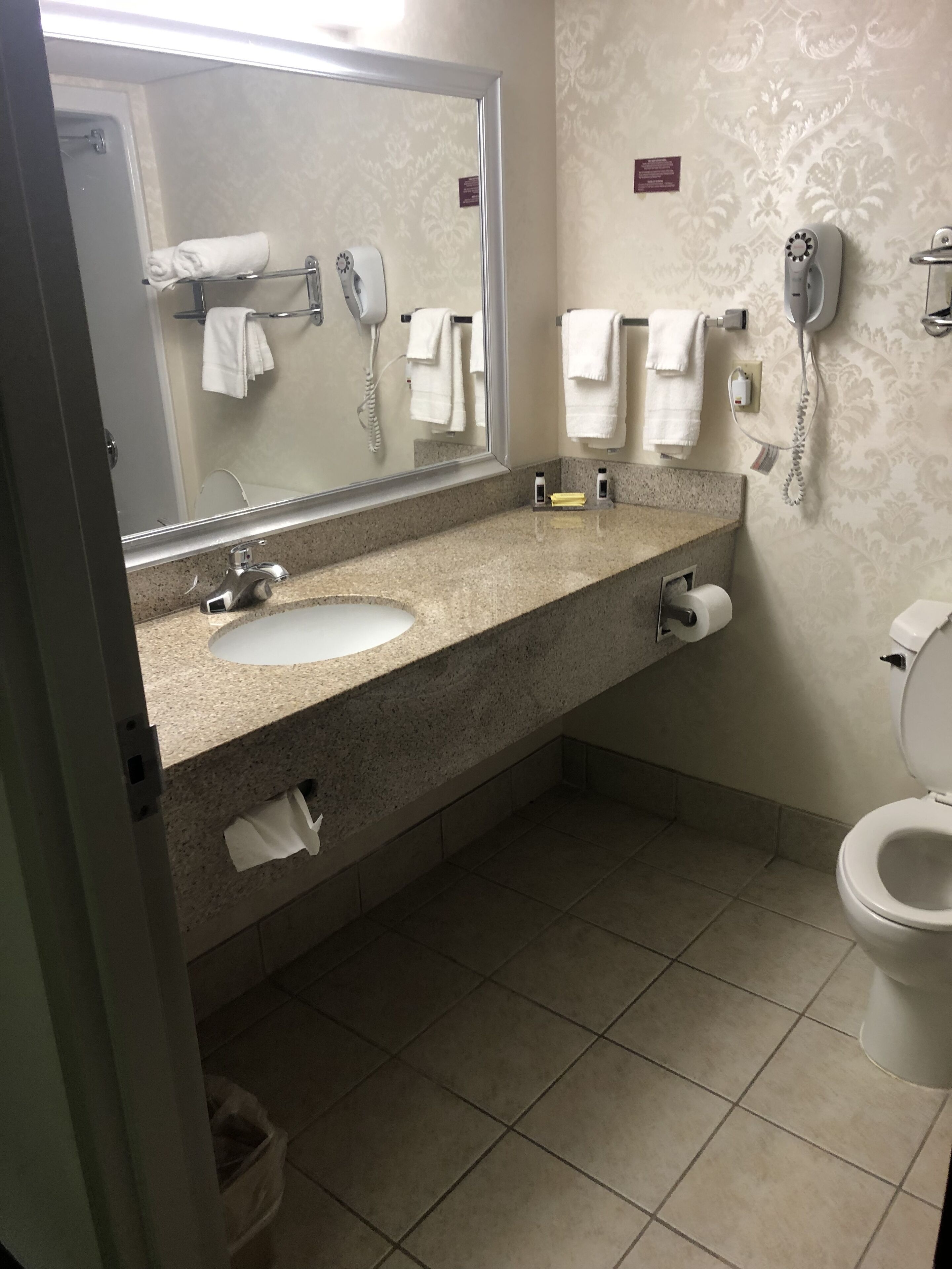 A bathroom with a sink, mirror, towel rack, toilet, and a hairdryer.