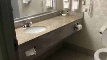 A bathroom with a sink, mirror, towel rack, toilet, and a hairdryer.