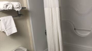 Un baño con inodoro, ducha con cortina a cuadros y un perchero con toallas dobladas.