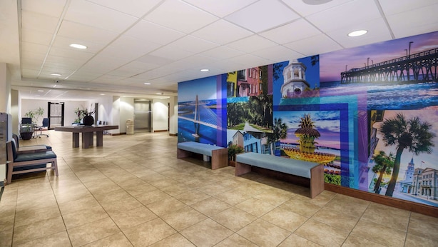 A hotel lobby with a tiled floor, a reception desk, and a mural depicting various cityscapes and landmarks.