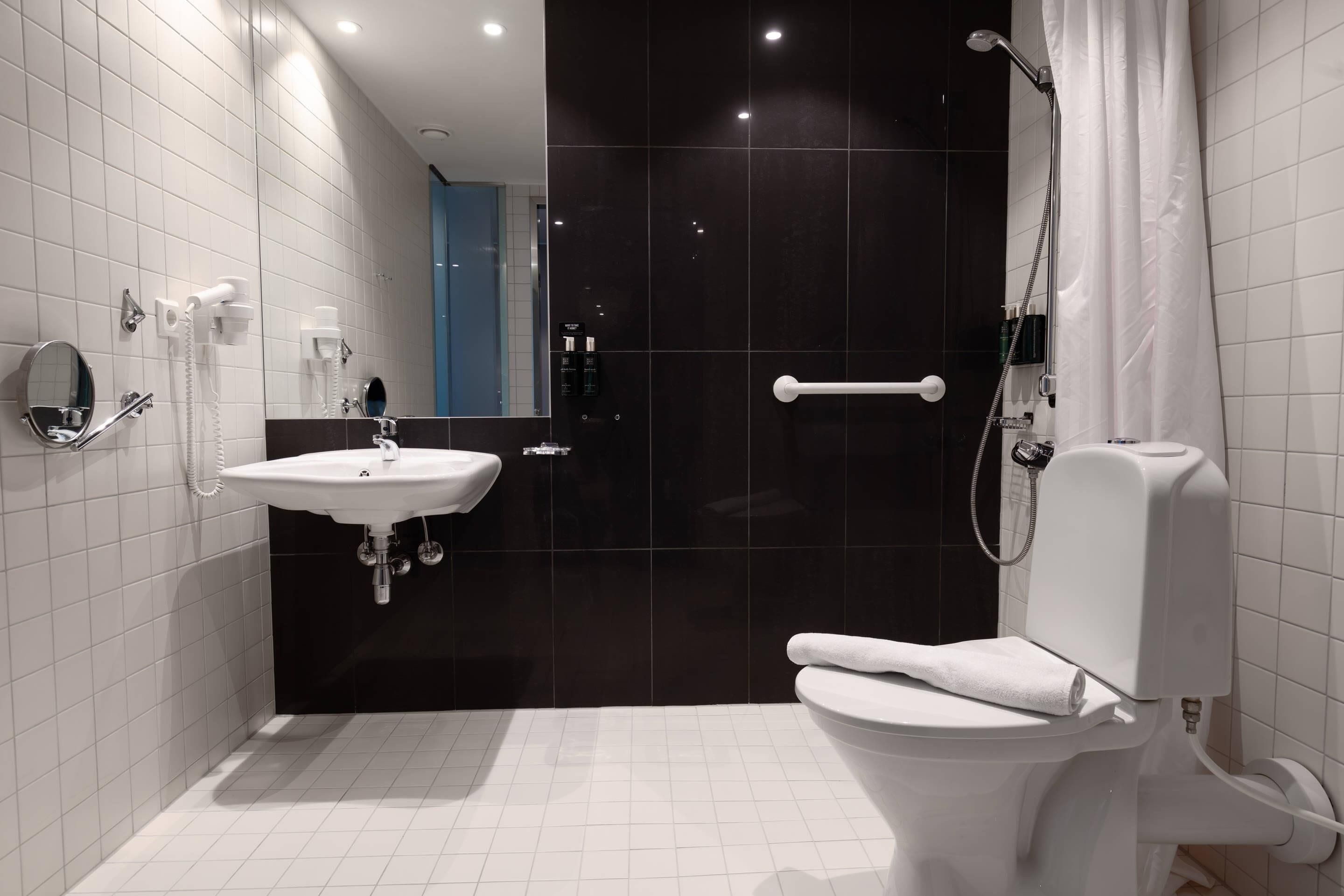 Een moderne badkamer met een wit wastafelmeubel, toilet en douche.
