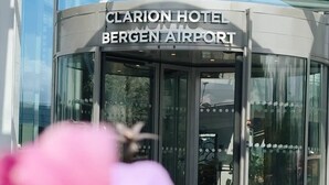 Entrada del Hotel Clarion, con fachada de vidrio y puerta giratoria.